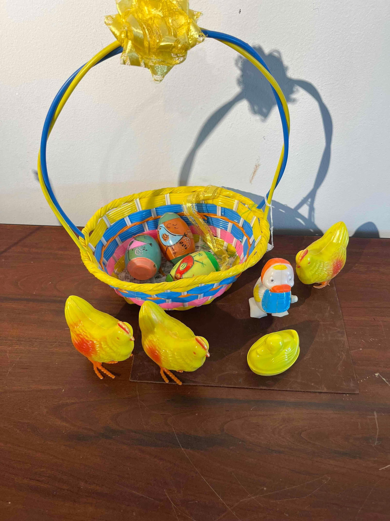 Easter Novelty Toys & Woven Basket: A South Korean woven plastic Easter basket accompanied by a group of coordinated plastic novelty toys and decorative containers. The basket is constructed from multi-colored woven strips in yellow,