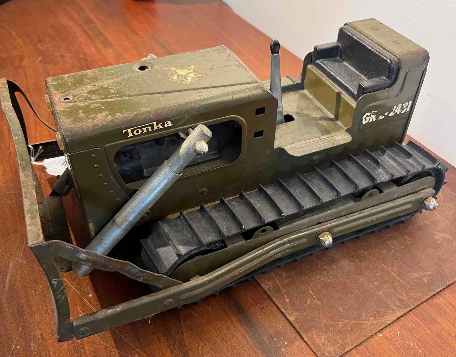 Tonka Steel Military Bulldozer GK-2431: This is a Tonka pressed steel military bulldozer finished in olive drab paint. The toy is constructed from heavy-gauge pressed steel and features a manual lever-operated front blade and black rubber c