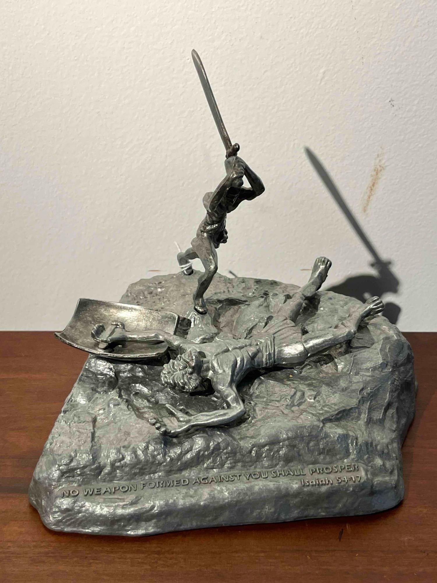 Vincent Heller David & Goliath Pewter: A cast pewter sculpture by Vincent Heller depicting the biblical confrontation between David and Goliath. The work features a young, athletic David standing atop a textured, rock-like integral base wi