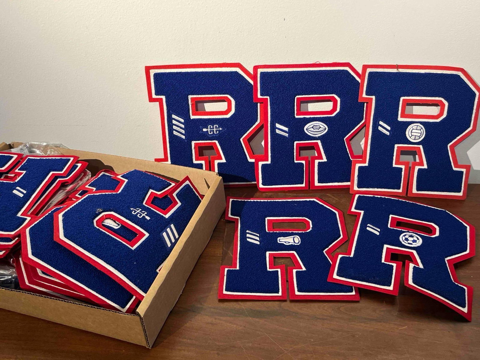 Chenille Varsity Patches R w/ Inserts: An assortment of three-layer chenille varsity letterman jacket patches in the form of a block letter R. Each patch is constructed with a royal blue chenille body layered over a white felt middle and a
