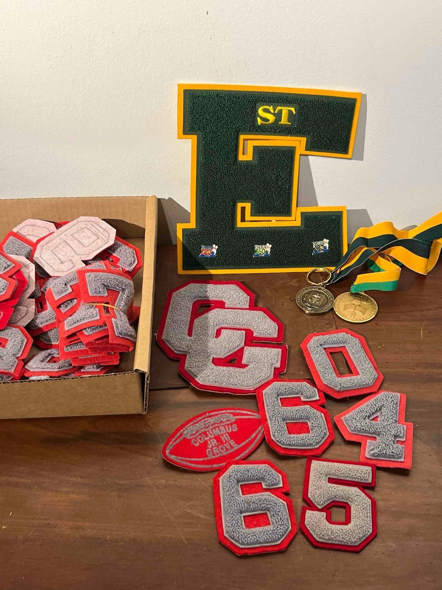 Columbus Grove Scholastic Memorabilia: This lot consists of an assortment of high school and collegiate style athletic and academic memorabilia. A large green and yellow chenille varsity letter E is mounted on a yellow backing. The letter 