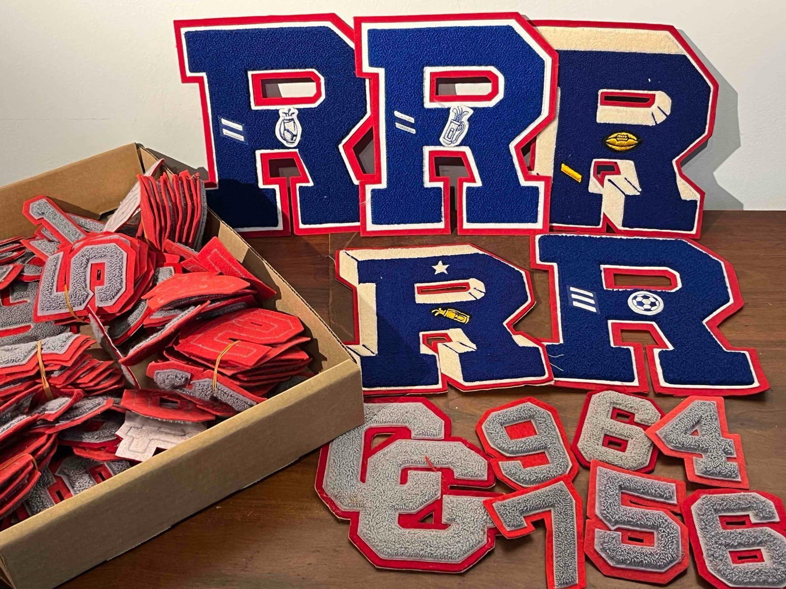 Chenille Varsity Letter/Num Patches: An assortment of athletic varsity patches featuring chenille construction on felt backings. The group is primarily composed of large letter R patches in a palette of royal blue, white, and red. Severa