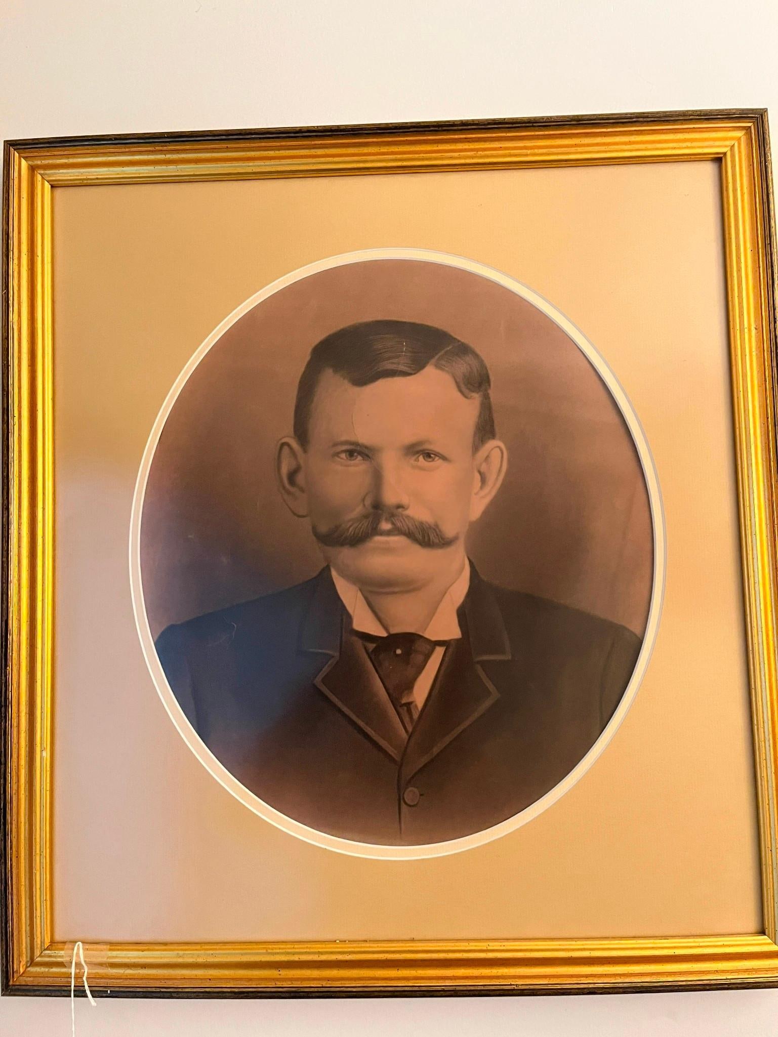 Crayon Gentleman Portrait, Gilt Frame: A large format crayon portrait enlargement depicting a bust length formal portrait of a gentleman. The subject features a prominent handlebar mustache and is dressed in a dark morning coat over a high