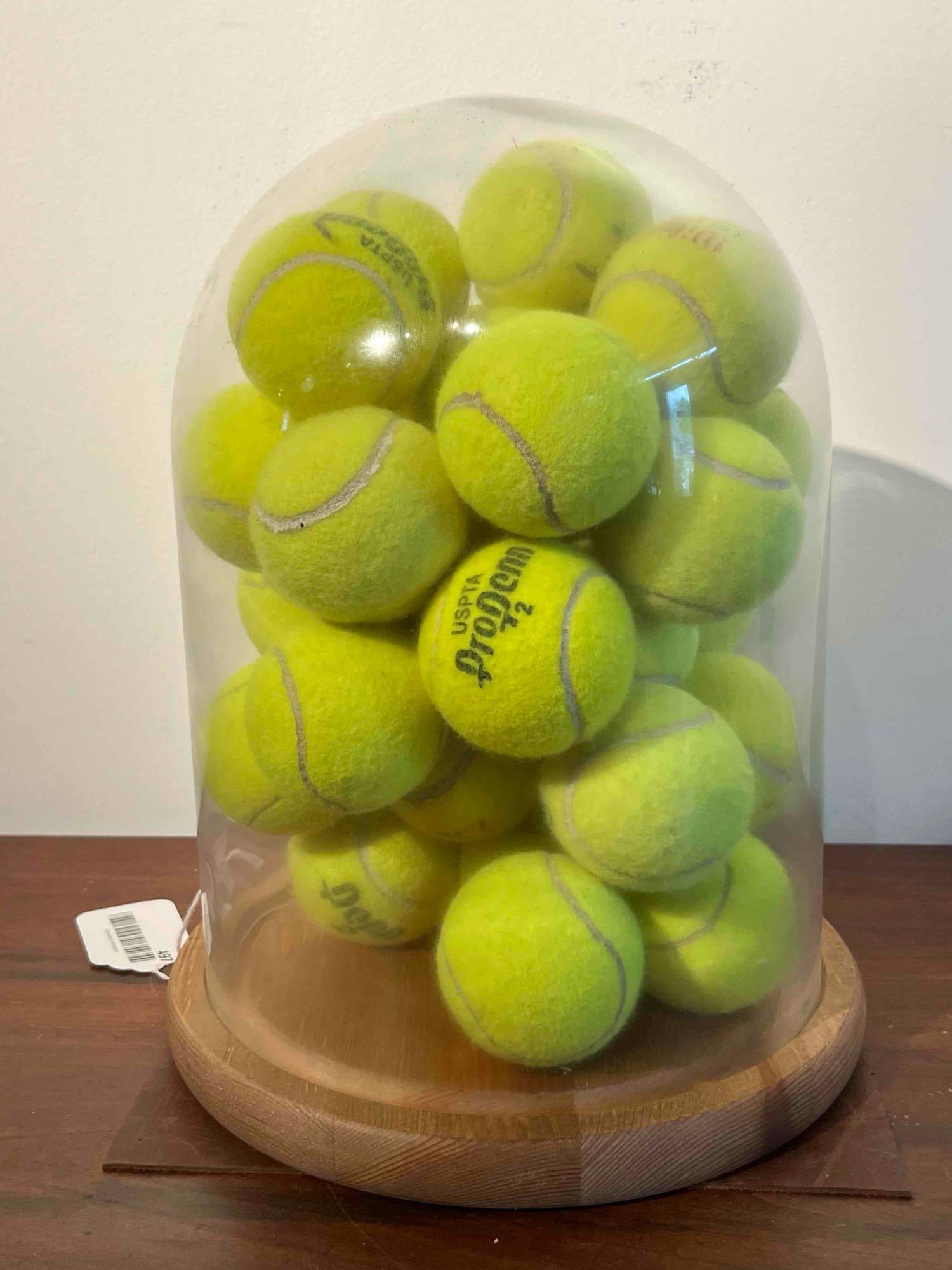 Used Tennis Balls, Glass Cloche & Base: A decorative novelty display featuring an assortment of used tennis balls within a clear glass cloche on a circular wooden base. The tennis balls show signs of use, including fuzzing and discoloration
