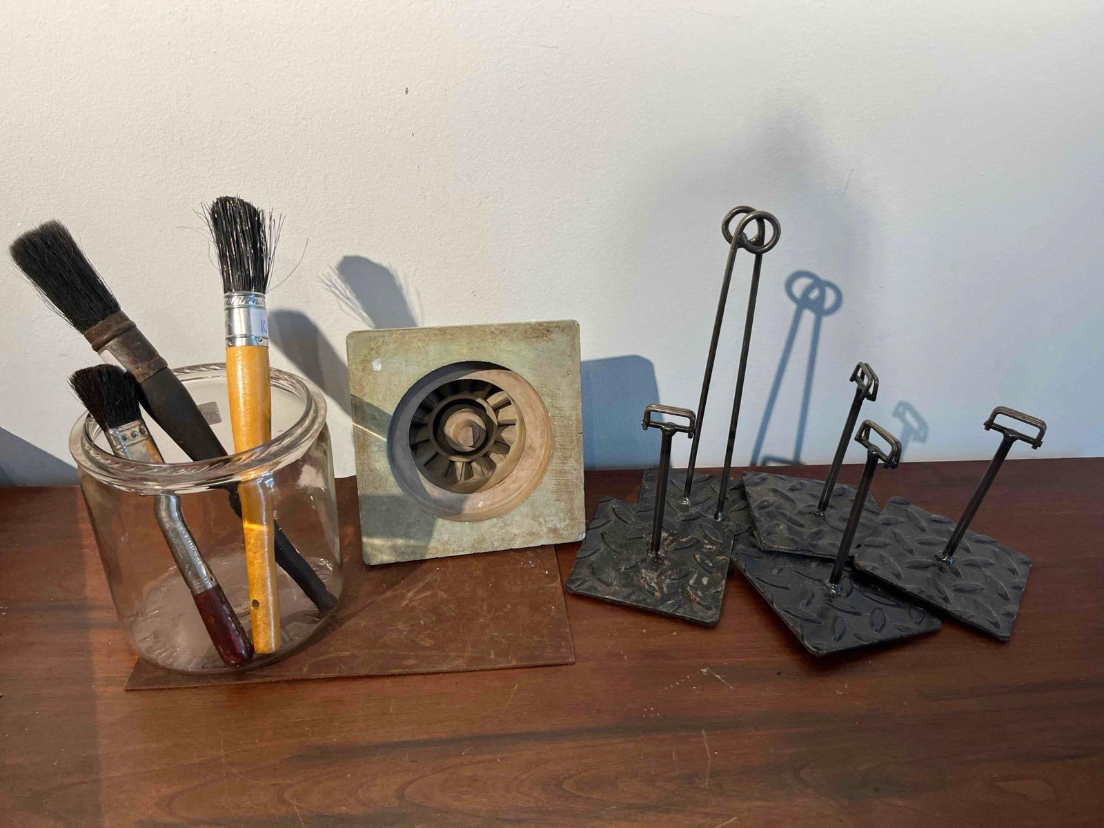 North Carolina Glass Jar & Steel Stands: This collection of industrial and utilitarian objects consists of a molded clear glass jar, a sculptural foundry pattern, and five custom-welded steel display stands. The glass storage jar features em