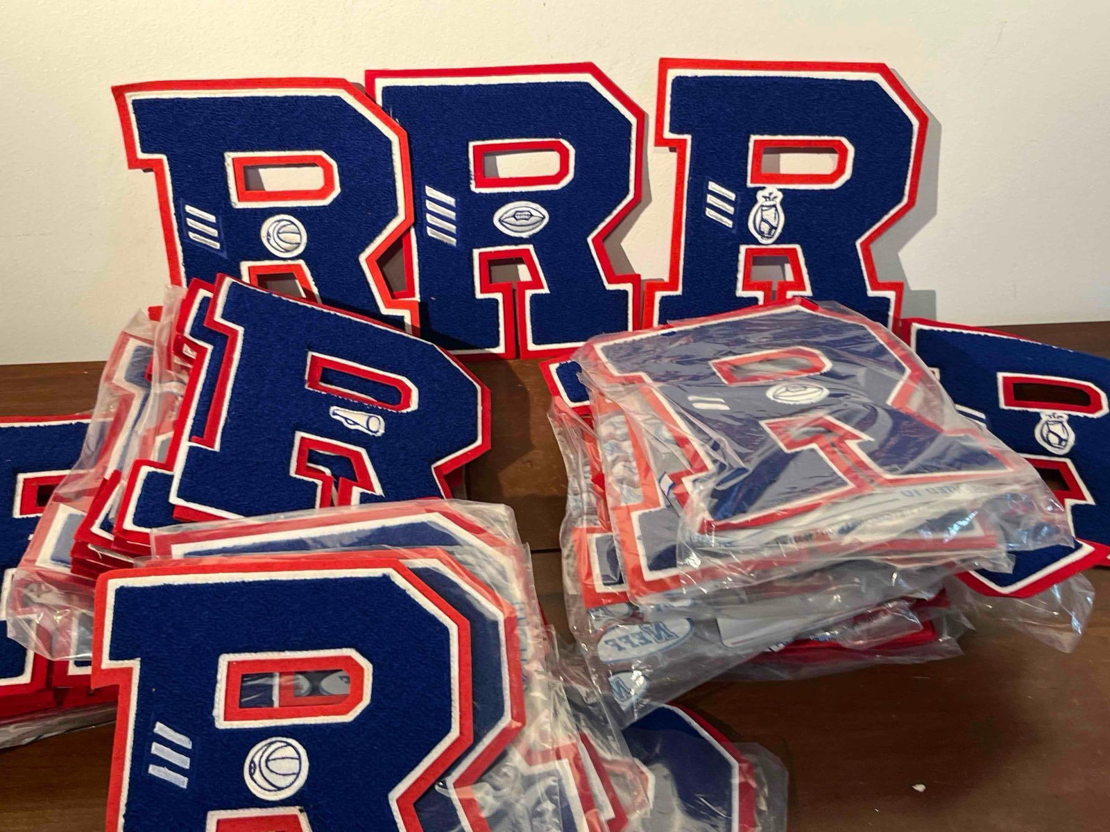 Neff Chenille Letter R Patches w/ Icons: This collection consists of a large quantity of varsity award patches, each fashioned as a capital letter R. The patches are constructed with a navy blue chenille body layered over a white and red tie