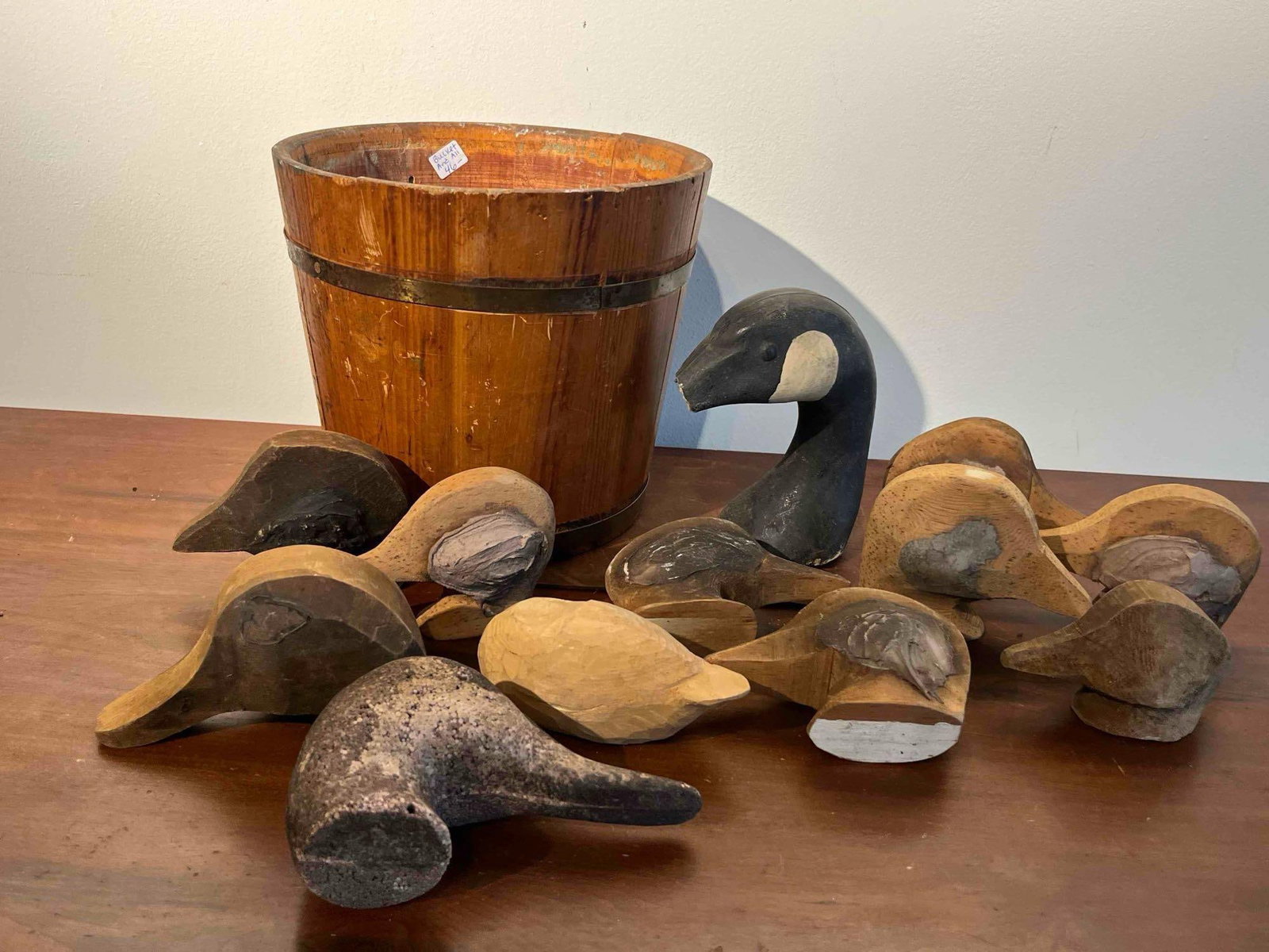 Carved Wood Decoy Parts & Stave Bucket: This lot comprises a group of hand-carved avian decoy elements and a wooden bucket. The collection includes a painted Canada goose head and neck with black and white markings, a textured head crafted