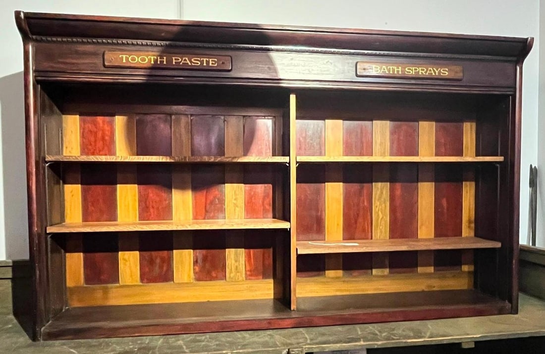 Late Victorian 2-Bay Apothecary Cabinet: A late 19th to early 20th-century apothecary or general store pharmacy display hutch. The unit features a two-bay design divided by a central vertical member and is topped with a prominent