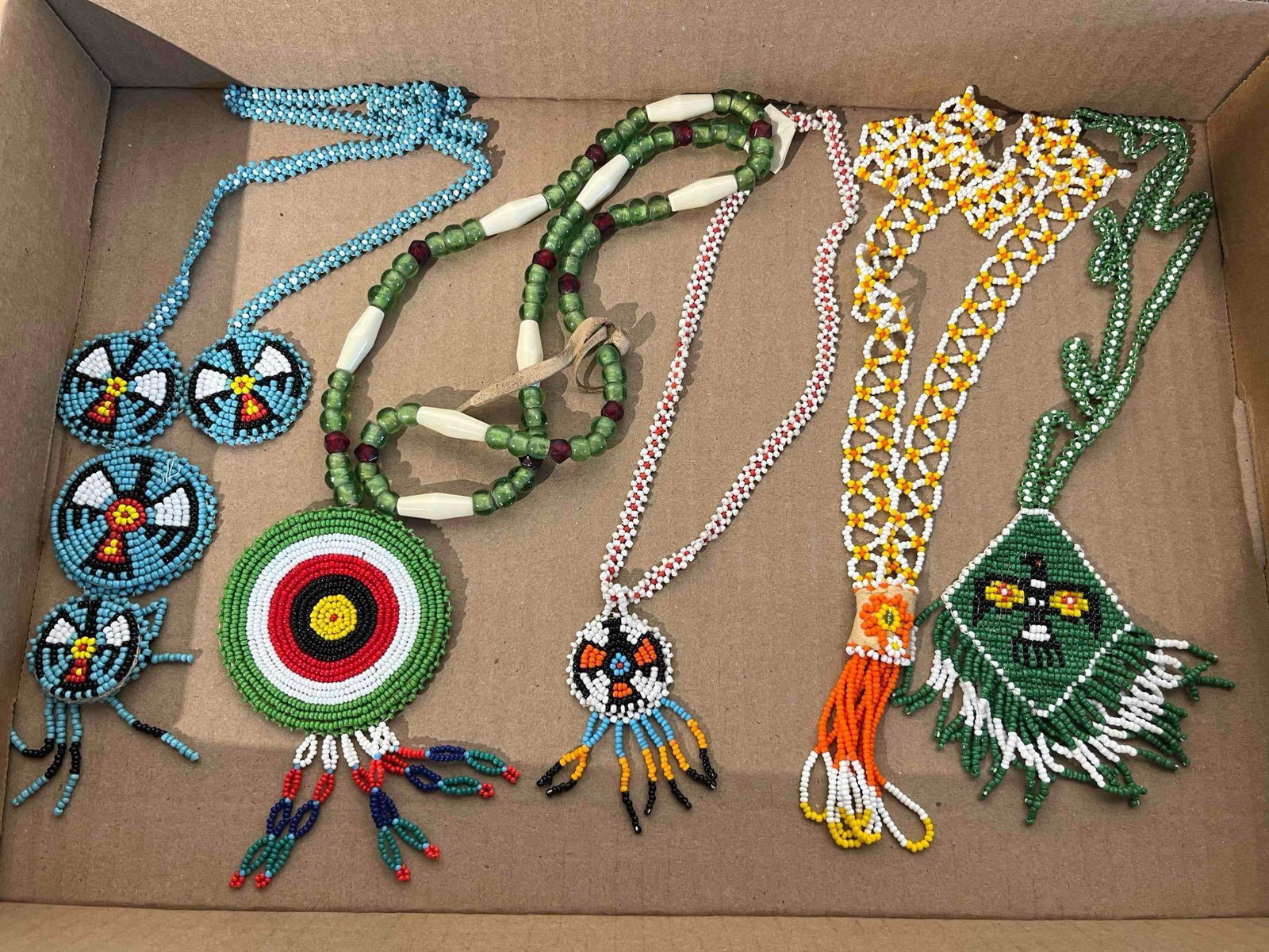 Indigenous N. Amer. Seed Bead Jewelry: An assortment of Indigenous North American-style beaded jewelry featuring several necklaces and medallions constructed with various glass seed bead techniques. The group includes circular loom
