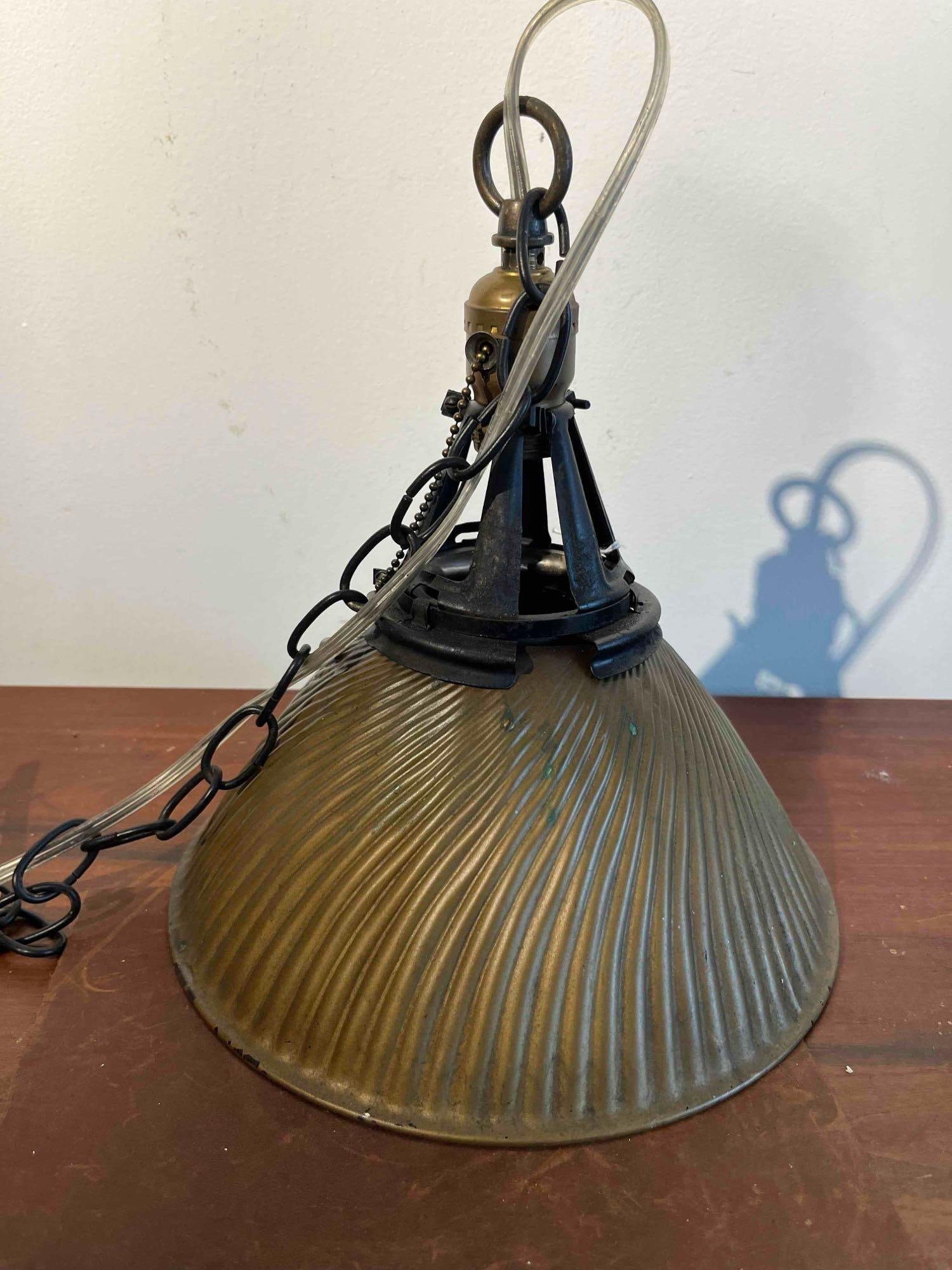 Industrial Prismatic Glass Pendant: This industrial pendant light fixture features a conical prismatic glass shade with a fluted exterior and a silvered mercury glass interior. The exterior of the shade is coated in a weathered bronze-t