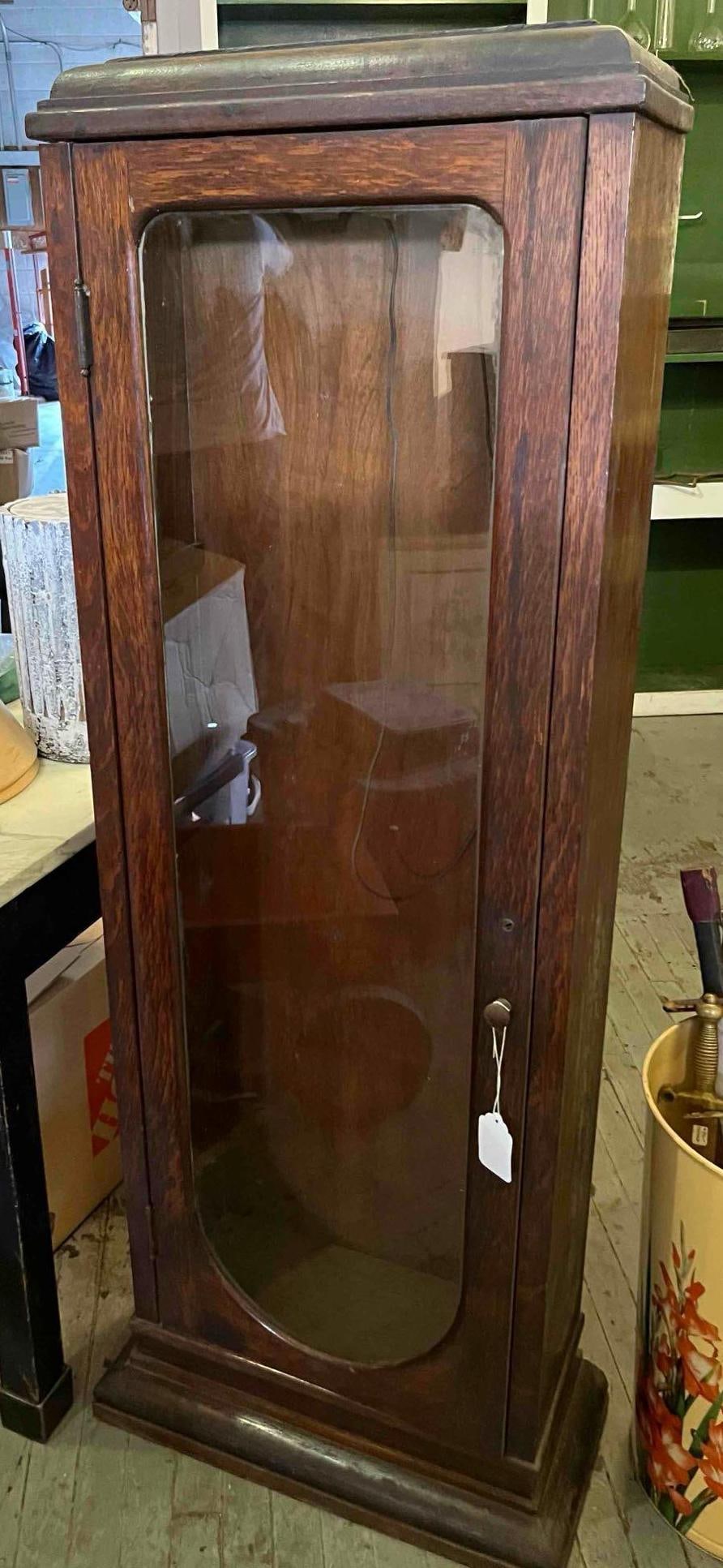 Tiger Oak Arched Glass Display Cabinet: A tall, narrow floor-standing curio display cabinet of one-piece construction, crafted from quartersawn oak featuring prominent medullary rays, commonly referred to as tiger oak. The single door conta