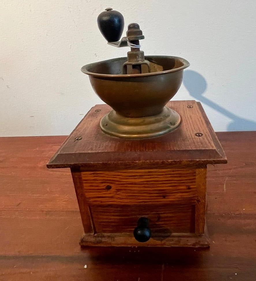 Wooden Box Coffee Mill w/ Brass Hopper: This manual hand-crank coffee grinder, commonly referred to as a lap mill, features a square-shaped wooden body with a prominent grain pattern. The body is constructed with joined edges and includes a