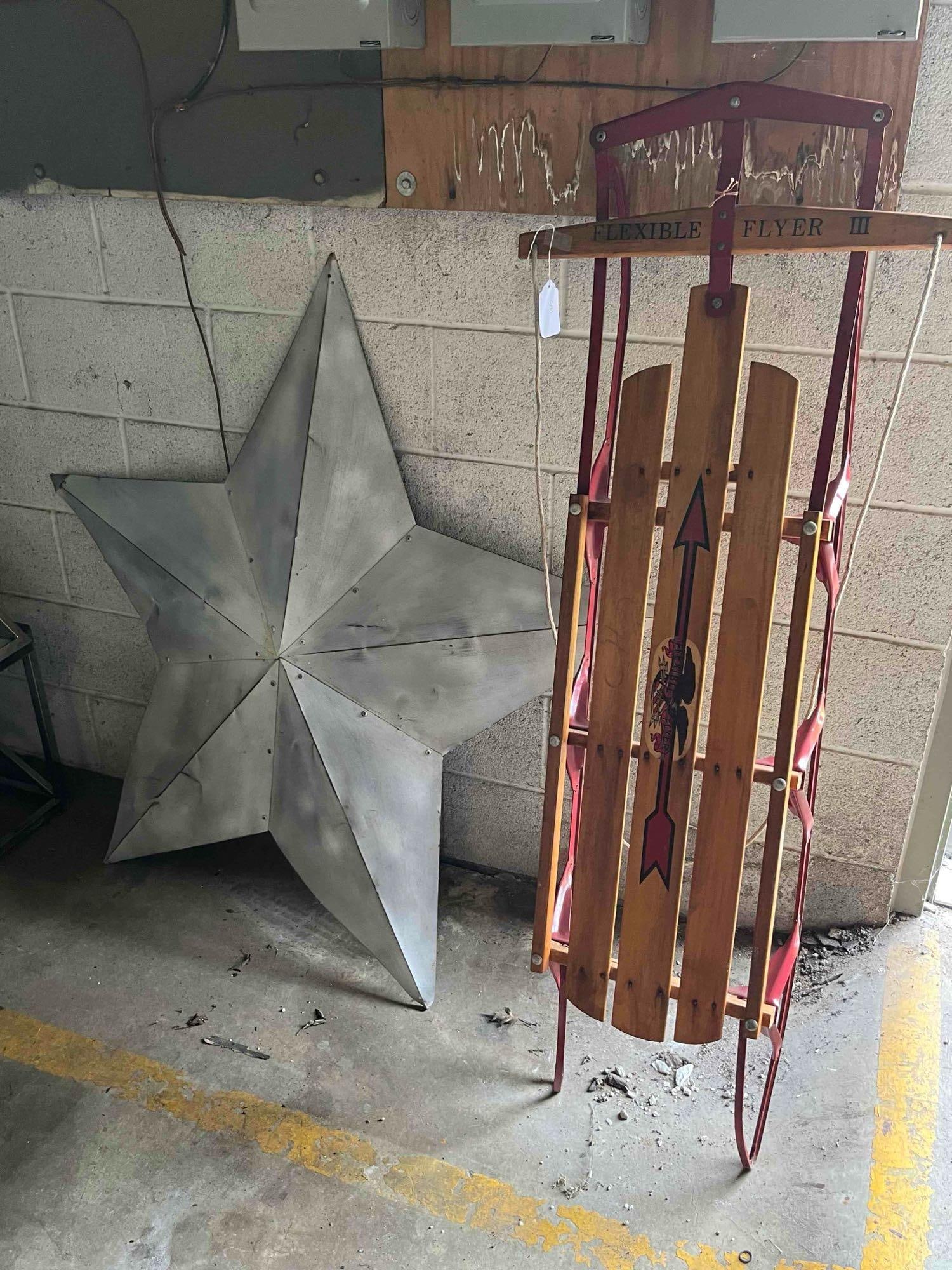 Flexible Flyer III Sled & Metal Star: Two decorative items comprising a steerable snow sled and a large three-dimensional barn star. The sled is constructed with three stained wooden deck slats mounted to a red-painted flexible steel