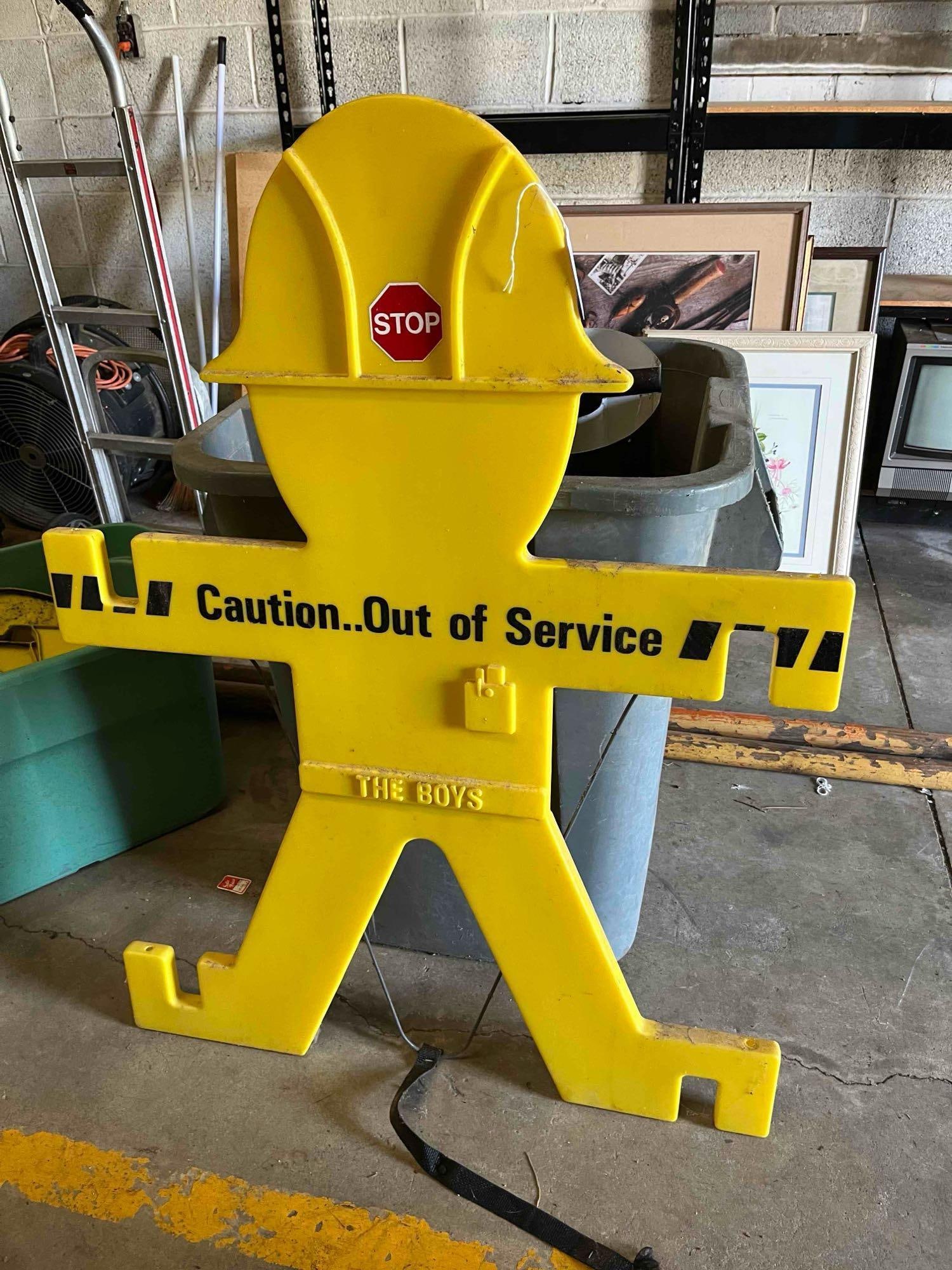The Boys Plastic Safety Barricade: A freestanding industrial safety barricade constructed of molded yellow high-density polyethylene. The unit is designed in the shape of a stylized human figure wearing a hard hat with outstretched