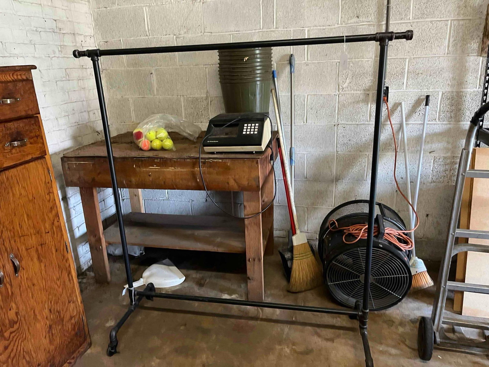 Rolling Industrial Pipe Garment Rack: This rolling garment rack is constructed from black-finished industrial iron piping and fittings. The design features a single horizontal top rail for hanging items, supported by two vertical