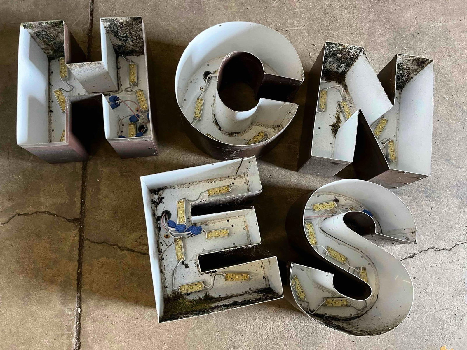 Metal LED Letters: Individual metal channel sign letters. Each letter features a fabricated metal housing with a brown exterior finish and a white-painted interior designed for light reflection. The letters are fitted