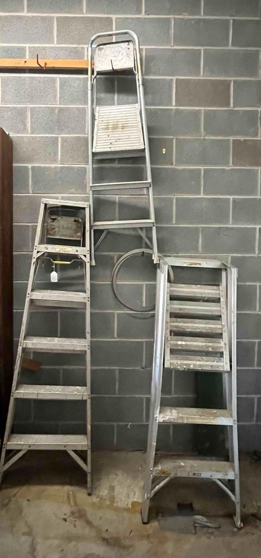 3 Aluminum Stepladders: A collection of three aluminum ladders of varying sizes and designs. The assortment includes a 6-step aluminum stepladder featuring riveted construction with cross-bracing on the bottom step and rear