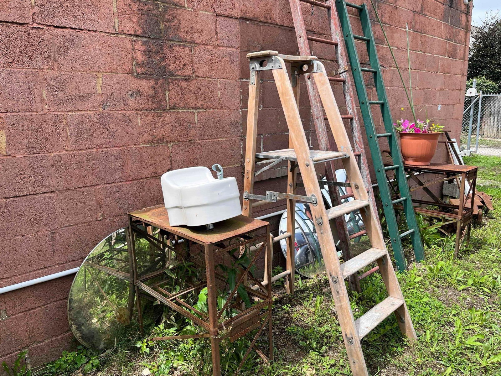 Salvage, Porcelain, Yard Decor, Fountain & Ladders: This collection features a diverse assortment of industrial and architectural salvage components. The primary piece is a wall-mounted drinking fountain made of white porcelain-enameled vitreous