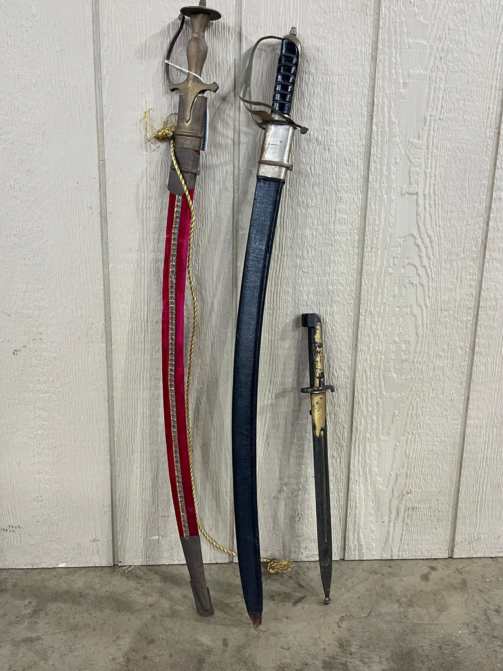 Final check. 39 characters. No: This lot comprises a trio of edged weapons of varying origins and styles. The first item is a 20th-century Indian talwar-style sword. The piece is constructed with a cast brass hilt featuring a
