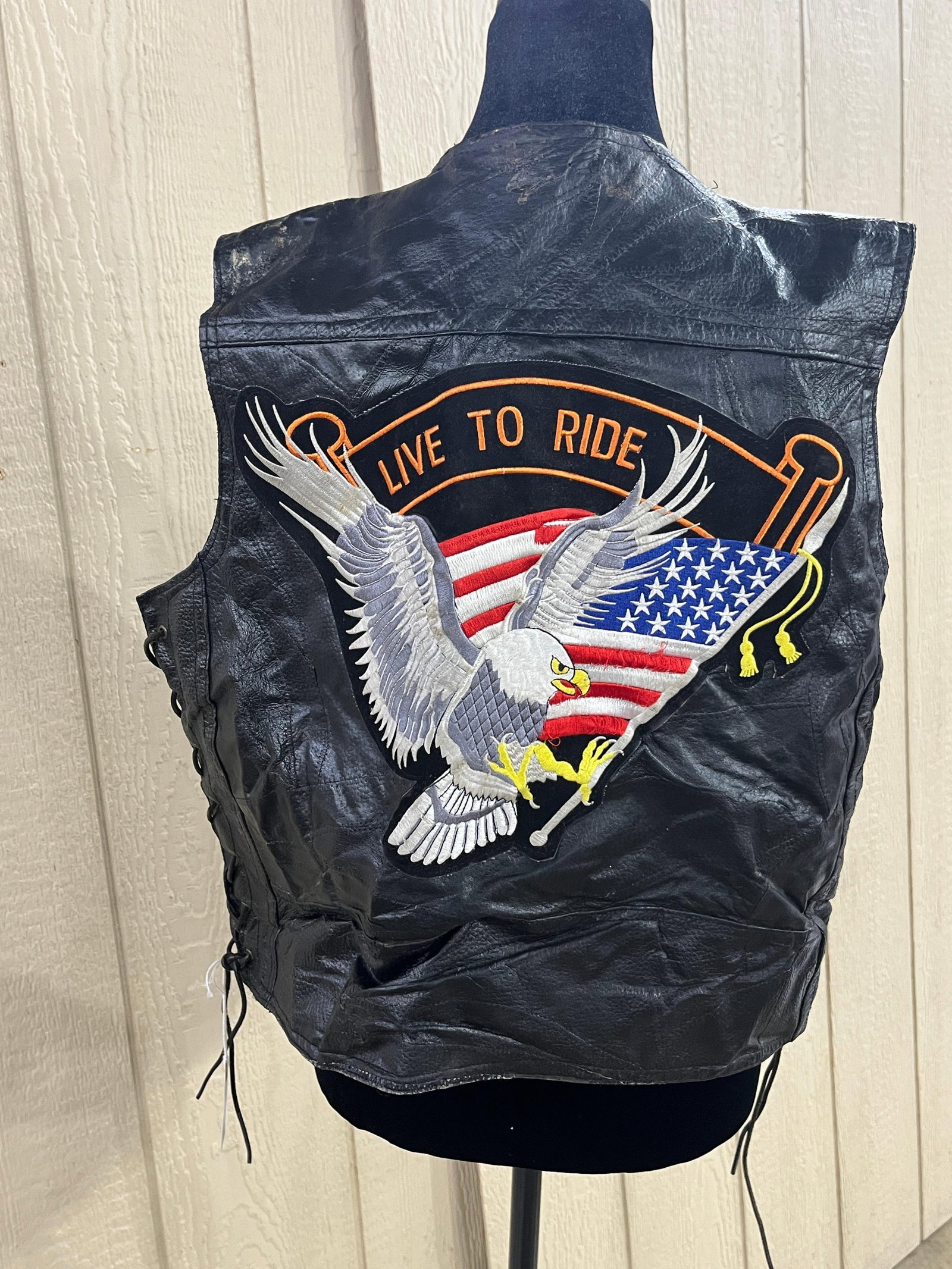 Pebble Leather Eagle Patch Biker Vest: This black pebble-grain leather motorcycle vest features a V-neckline and a four-snap front closure. The front is designed with four pockets, consisting of two horizontal welt pockets at the waist
