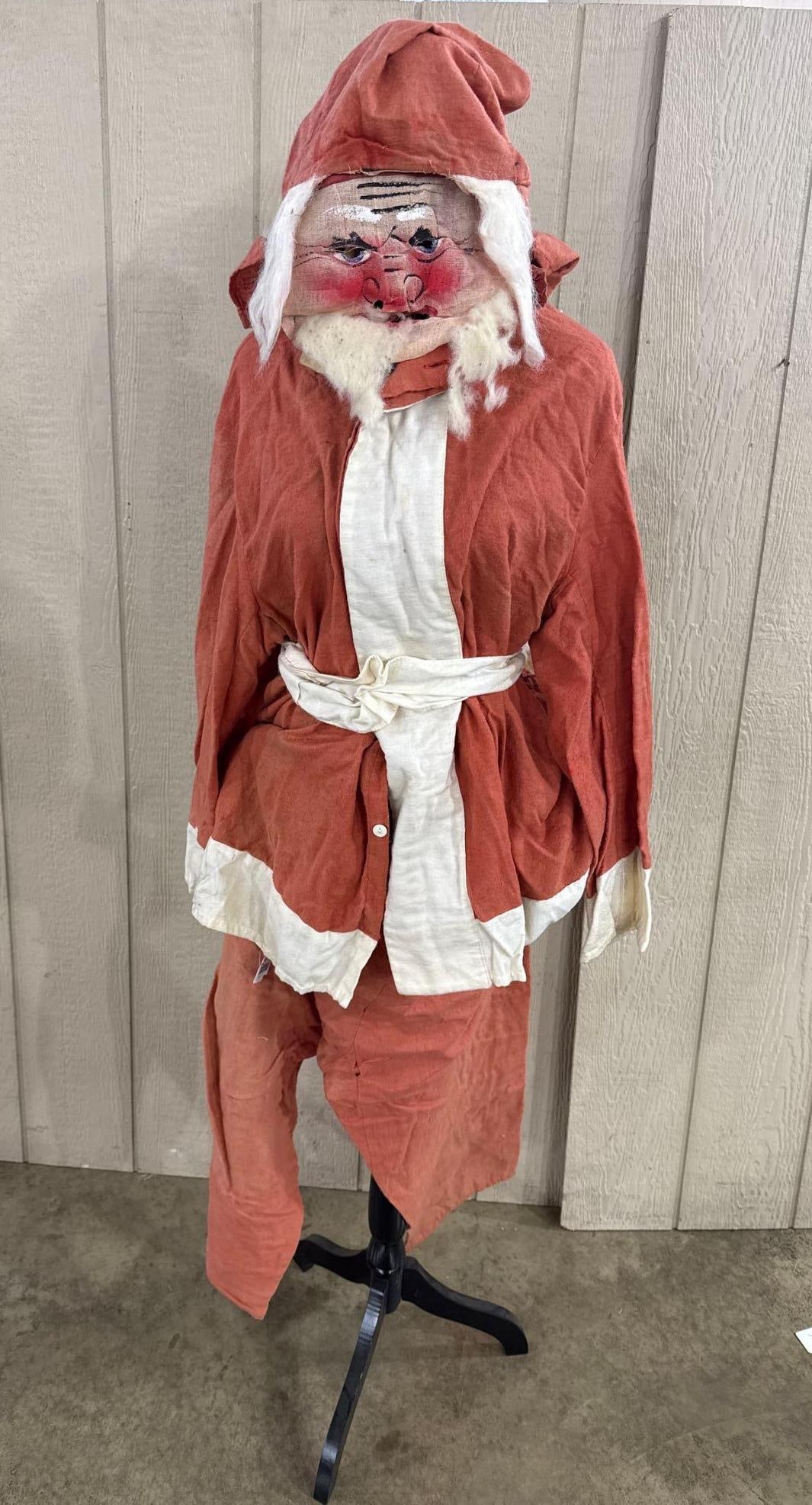 1940s Santa Costume w/ Painted Mask: A two-piece Santa Claus costume ensemble consisting of a hooded tunic with an integrated mask, matching trousers, and a coordinating waist sash. The suit is constructed from a coarse-weave natural