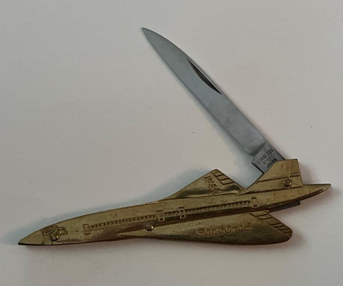 Japanese Concorde G-BSST Pocket Knife: A Japanese single-blade folding pocket knife designed in the figural shape of the Concorde supersonic transport aircraft. The handle is constructed from cast metal with a gold-toned finish, molded to 