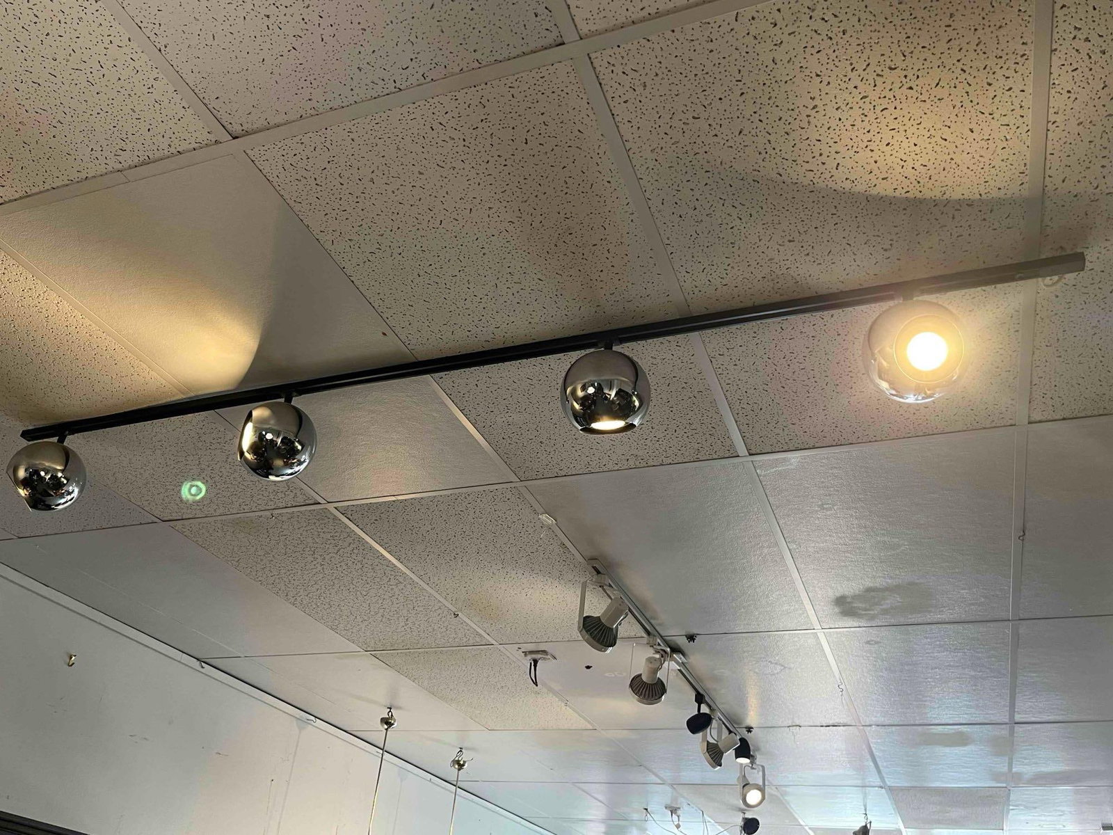 Set Polished Chrome Eyeball Track Heads: A set of track lighting featuring adjustable spherical heads. Each head is constructed of metal with a polished chrome finish and a circular aperture for bulb placement. The heads are attached to a bl