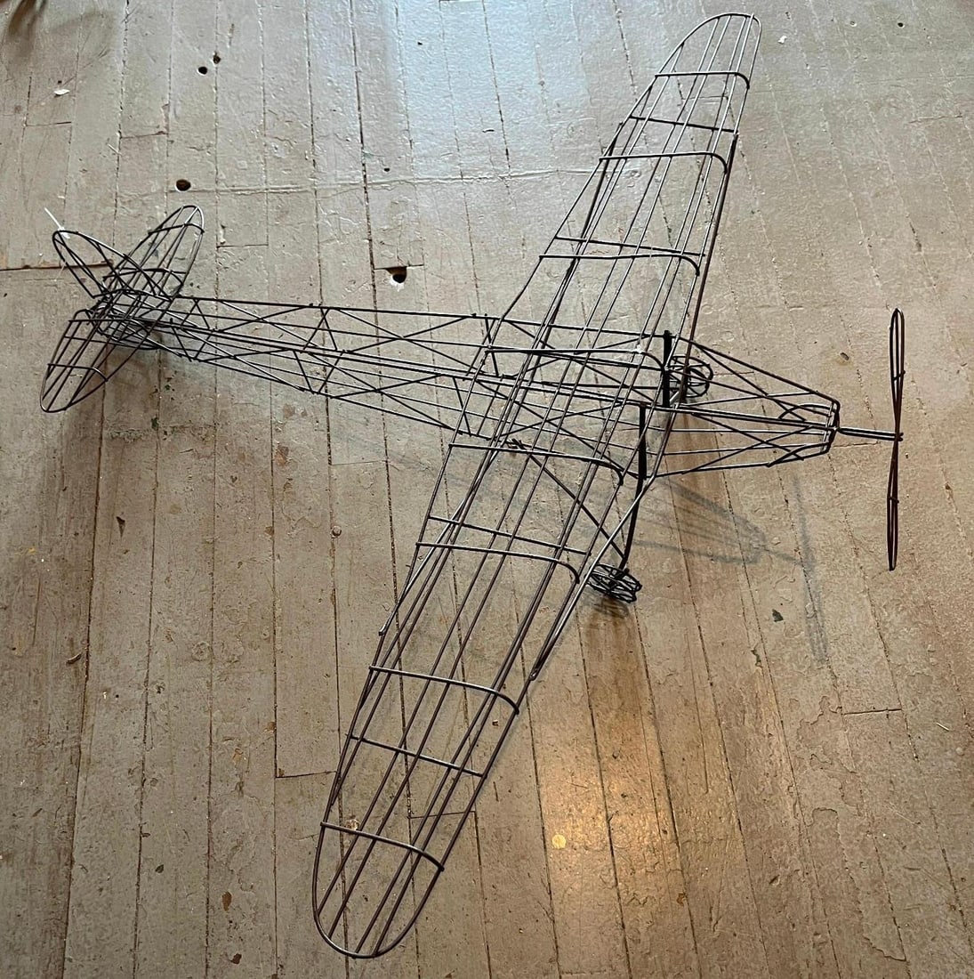 Wireframe Model Airplane Sculpture: A large wireframe model of a high wing monoplane, constructed entirely from hand-formed metal wire. The skeletal design represents a light aircraft stylistically reminiscent of a Piper J-3 Cub or Tayl