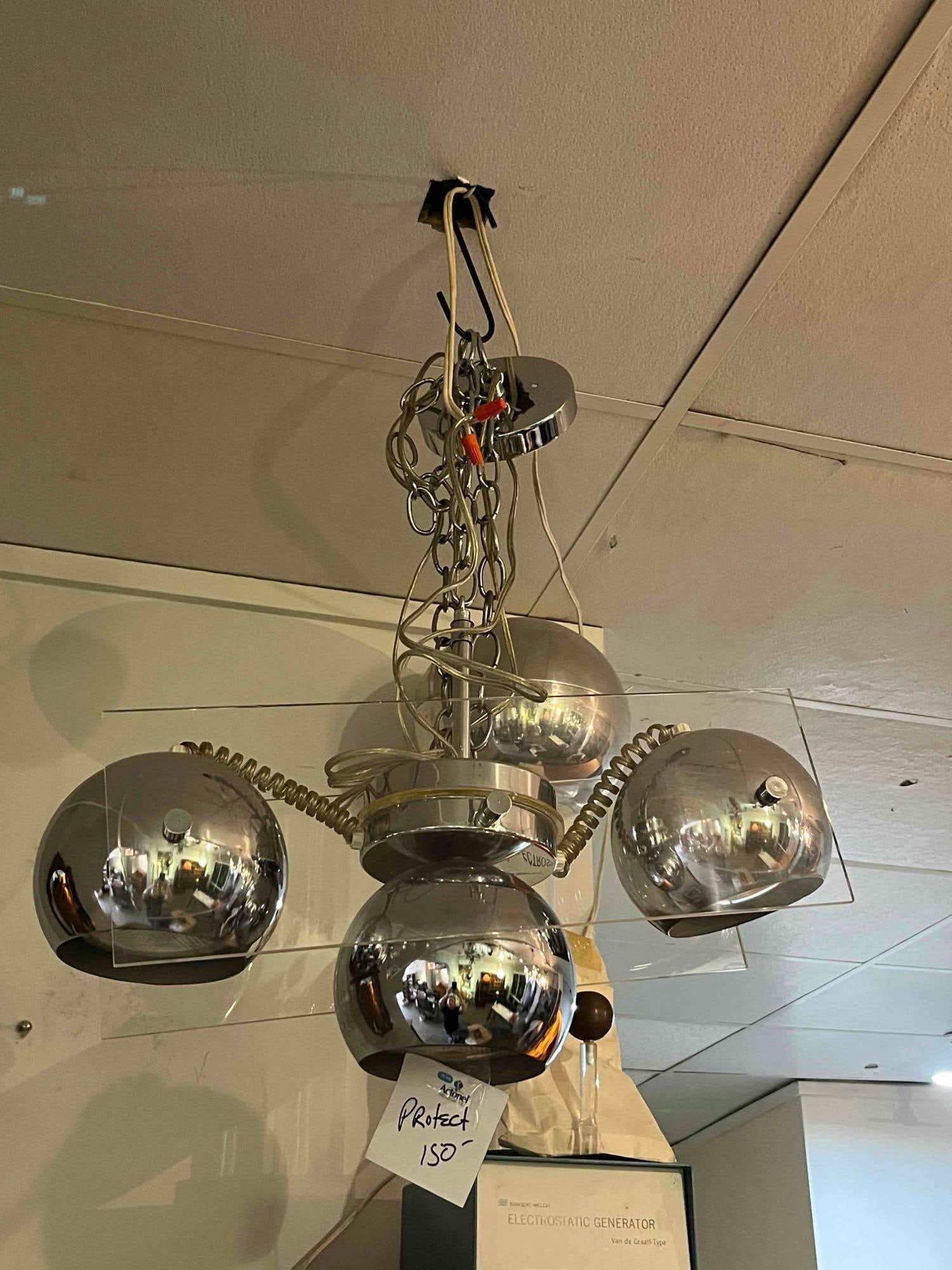 Chrome & Acrylic Eyeball Chandelier: A four-light chandelier featuring a polished chrome-plated metal and clear acrylic construction in the Space Age style. The fixture consists of a central cylindrical hub with four horizontal arms,