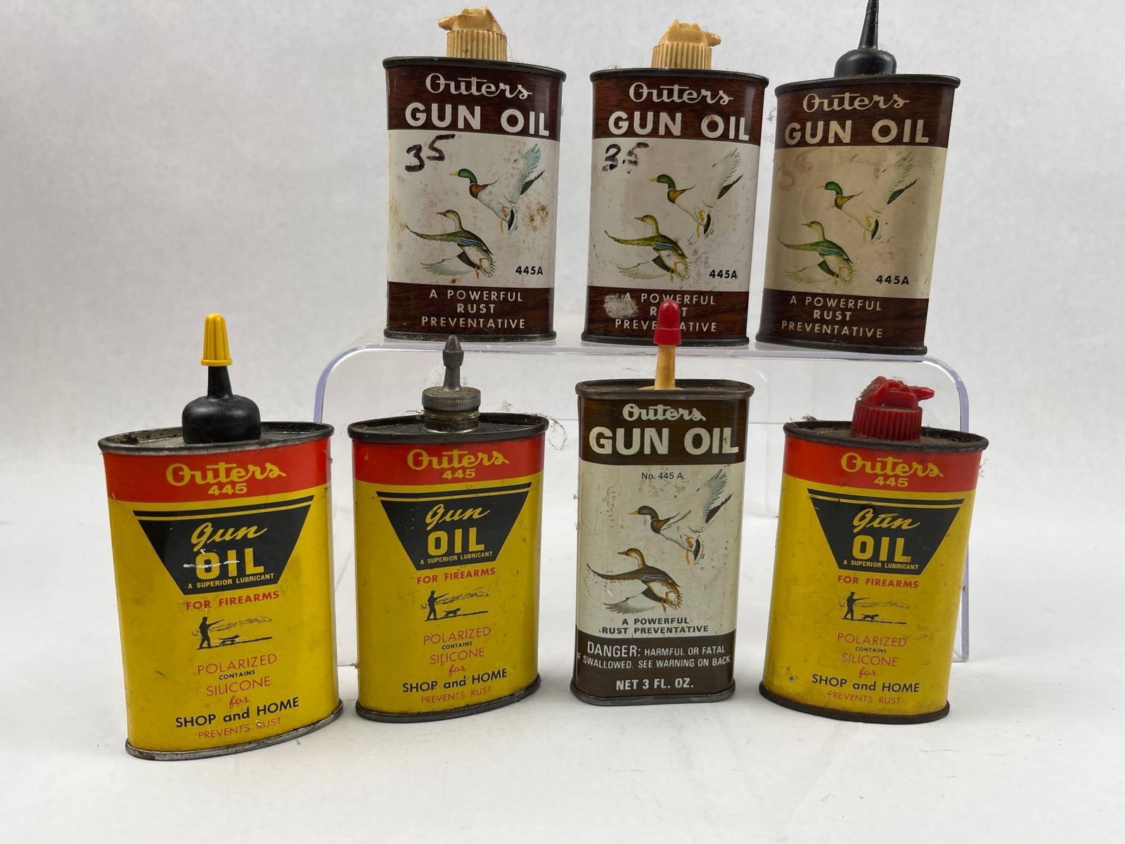 Outers Gun Oil & Rust Preventative Tins: A collection of lithographed metal 3 ounce containers produced by Outers Lab., Inc. of Onalaska, Wisconsin. The assortment includes two distinct label variations. The reverse of these tins provides