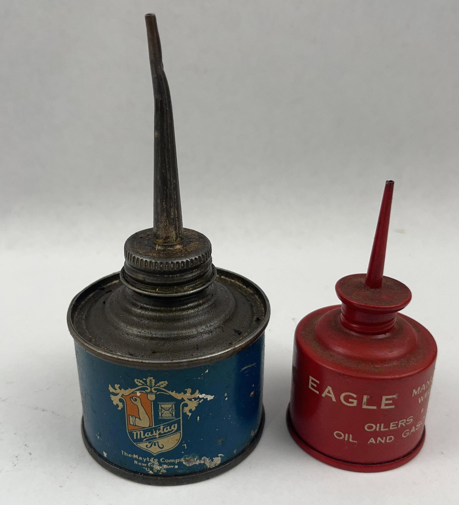 Maytag Blue Thumb & Eagle Red Oilers: A pair of vintage thumb-press metal oil cans. The front of the can features a multicolored coat-of-arms logo. Diameter of blue oiler: 2.5 inches Total height of blue oiler: 5.25 inches Diameter of