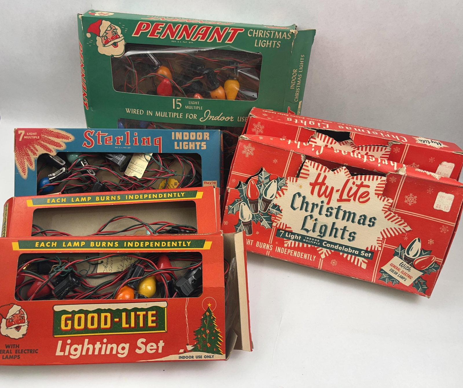 Vtg Pennant, Str. & Hy-lite Light Sets: A collection of five mid-20th-century indoor Christmas light sets in their original printed cardboard retail packaging. The assortment includes a green cardboard box printed with PENNANT REG. A blue