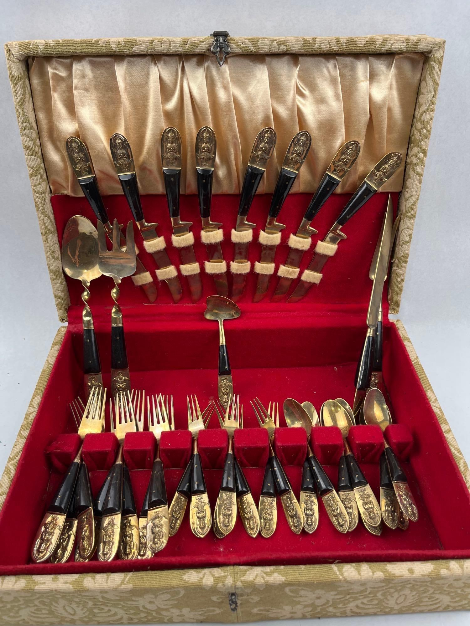 A Set of Thai Brass and Wood Flatware: A Thai brass and wood flatware service housed in a fabric-covered presentation case. The service is constructed from a gold-tone brass alloy and dark wood, with the wood handle scales secured by