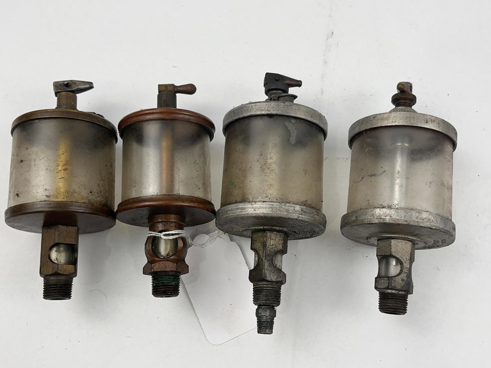 4 Lunkenheimer & Oil-Rite Lubricators: A group of four vintage industrial drip feed lubricators, also known as oilers, typically utilized for the gravity-fed lubrication of bearings on stationary steam or hit-and-miss gas engines. The