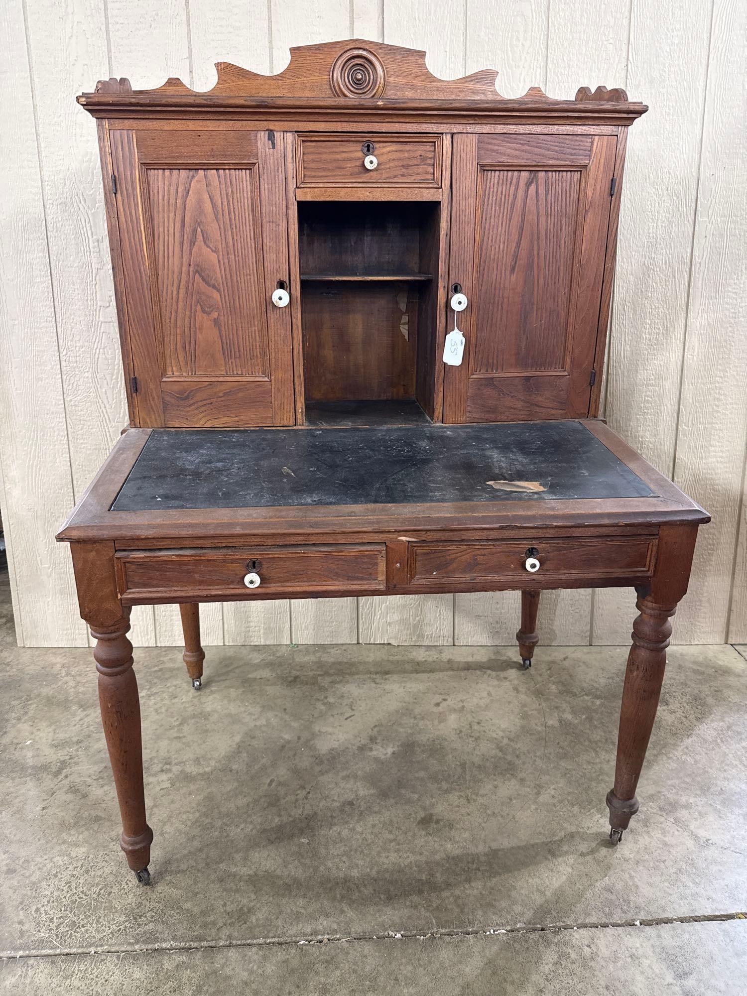 Plantation" means it's one of those: A late 19th-century American clerks or plantation-style desk constructed of oak. The base features a rectangular top with a black inset writing surface, possibly leather or oilcloth. The piece is desi