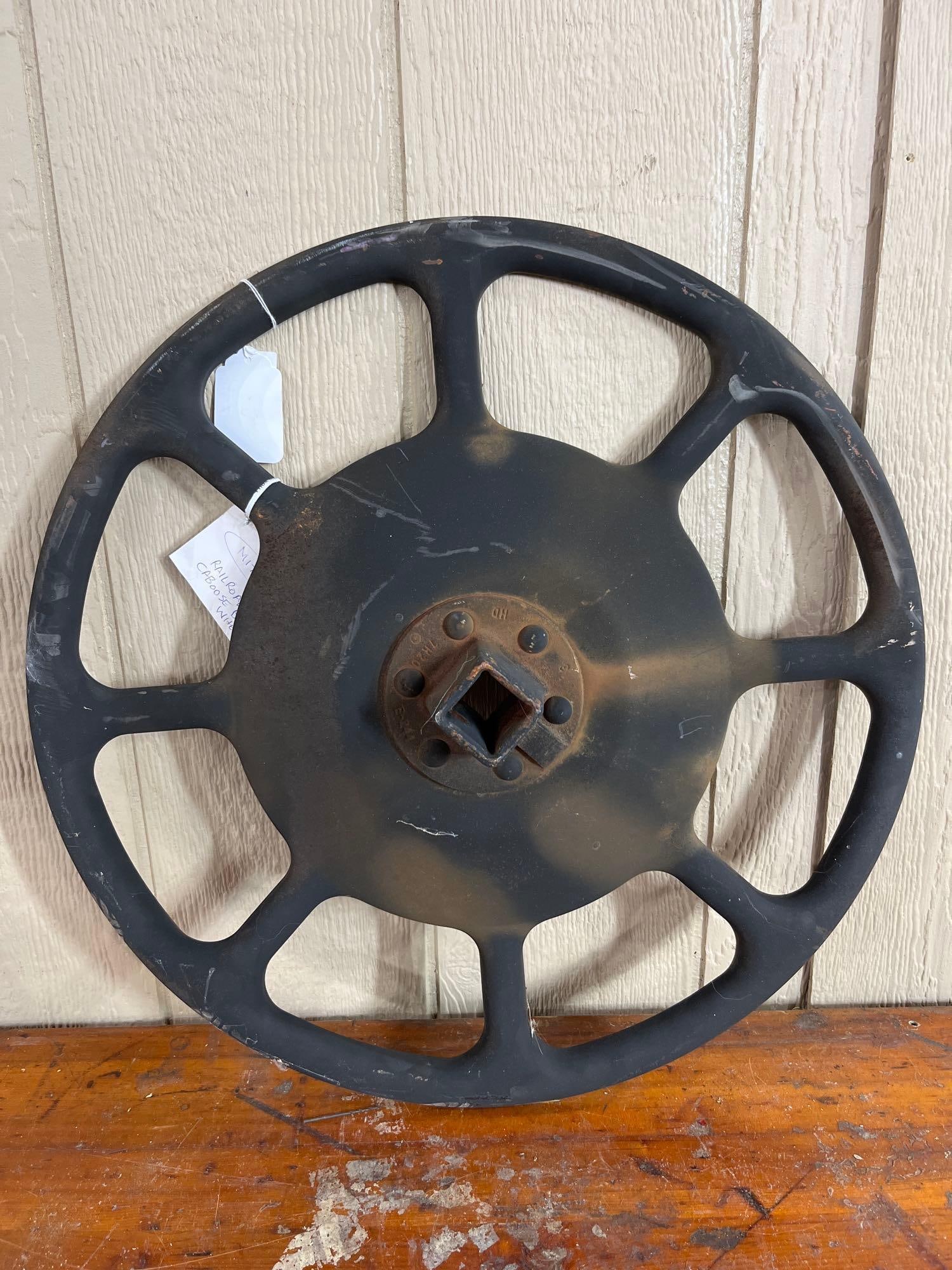 Cast Metal Railroad Caboose Brake Wheel: A cast metal hand brake wheel designed for railroad service, identified as originating from a caboose by a handwritten tag (photo 1). The wheel features an eight-spoke design connected to a solid