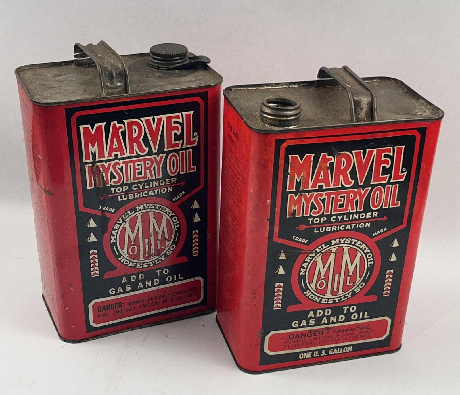 Pair Vtg Marvel Mystery Oil Tin Cans: A pair of vintage lithographed tin utility cans for Marvel Mystery Oil, manufactured by the Marvel Oil Company, Inc. of Port Chester, New York. Each container features a rectangular body with a metal 