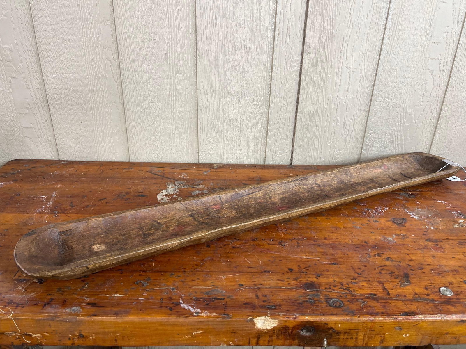 Hand-Carved Primitive Wood Dough Bowl: A primitive hand-carved wooden dough bowl or trencher of elongated proportions. The wood is finished in a medium brown tone with a heavy surface patina. Measurements/Notes: 42 x 8.5.