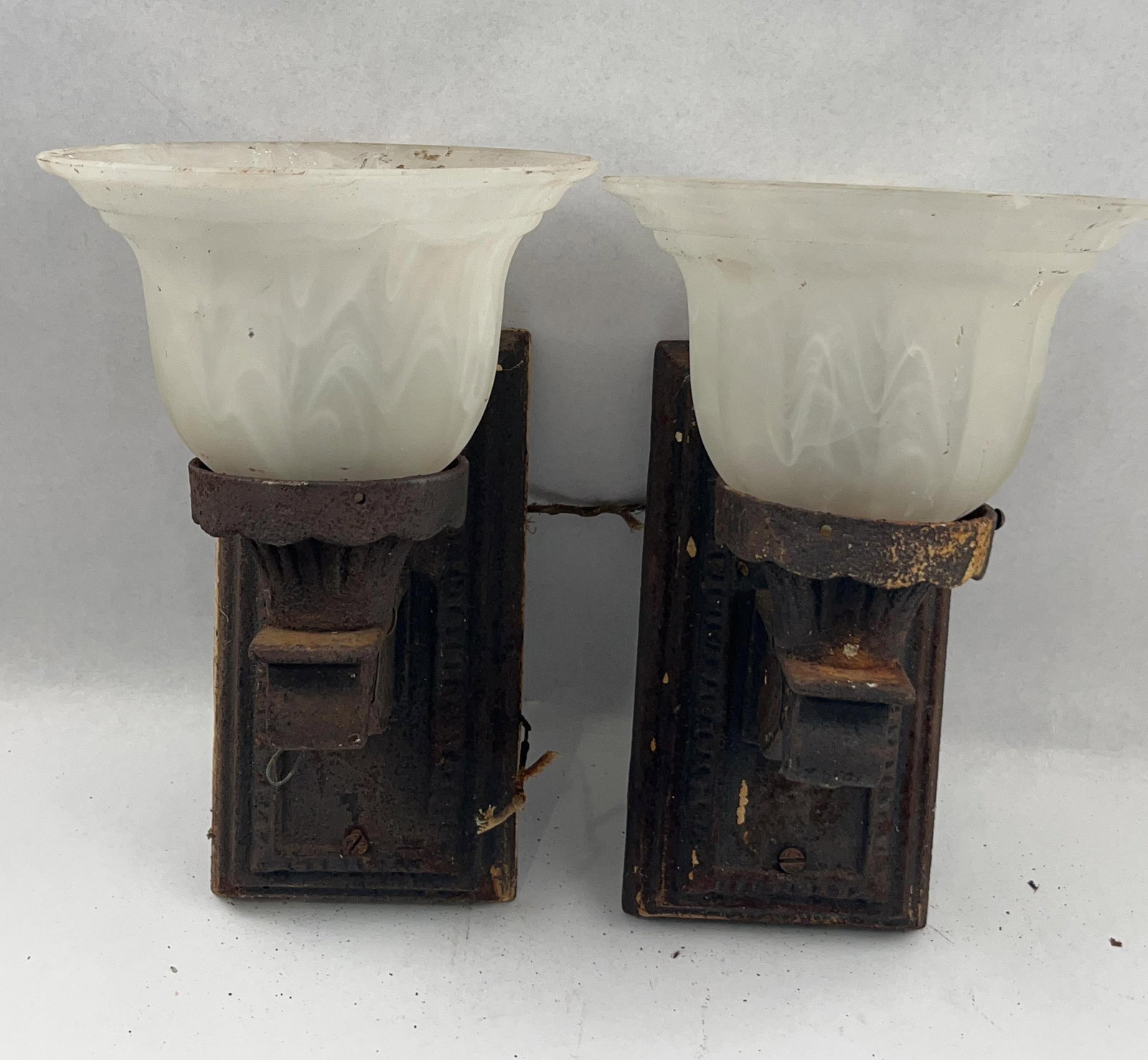 Pair Arts & Crafts Iron & Glass Sconces: A pair of antique American electric wall sconces dating to the early 20th century, approximately 1910s to 1920s. Each fixture features a heavy cast iron rectangular backplate decorated with molded