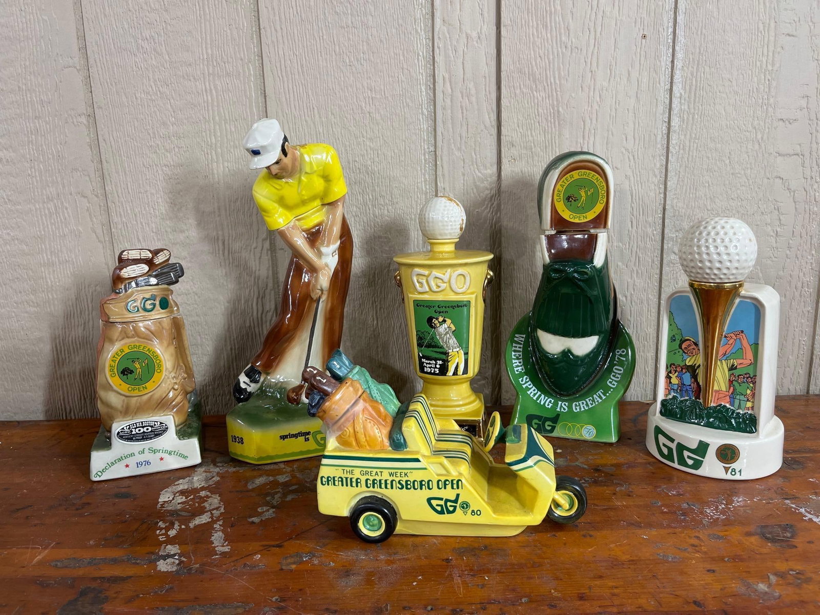 Set 6 Greater Greensboro Open Decanters: A collection of six ceramic liquor decanters produced between 1973 and 1981 to commemorate the Greater Greensboro Open (GGO) golf tournament in North Carolina. The 1973 decanter depicts a golfer