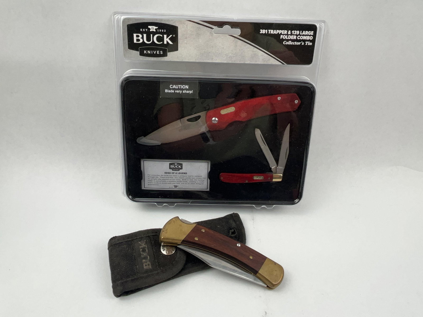 Buck Knives 110, 381 & 139 Tin Set: A three-piece lot of folding knives featuring a two-knife collector set and a separate lockback hunter. The collector set, contained within its original plastic retail packaging and a metal tin with
