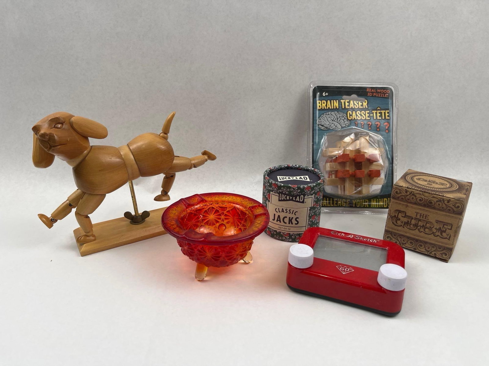 Vtg Toys, Puzzles & Objects Collection: A collection of toys, games, and decorative objects featuring an articulated wooden dog figure, amberina glassware, and various puzzles. The articulated dog figure is constructed from carved and turne