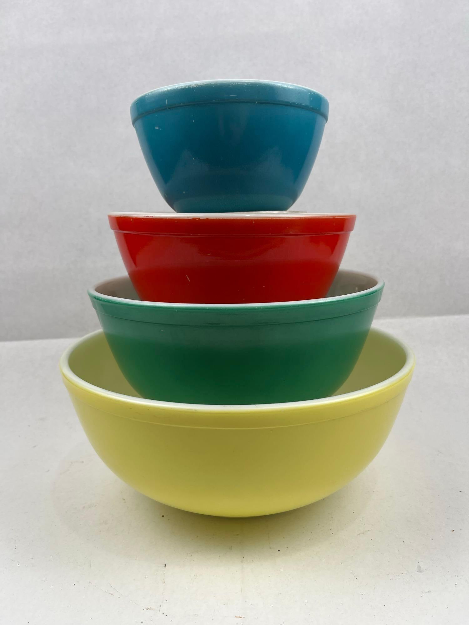 Set 4 Pyrex Primary Color Nesting Bowls: A set of four Pyrex graduated mixing bowls in the Primary Colors pattern. Each bowl is constructed of opaque white glass with a fired-on exterior color. The set includes four bowls in sizes typically