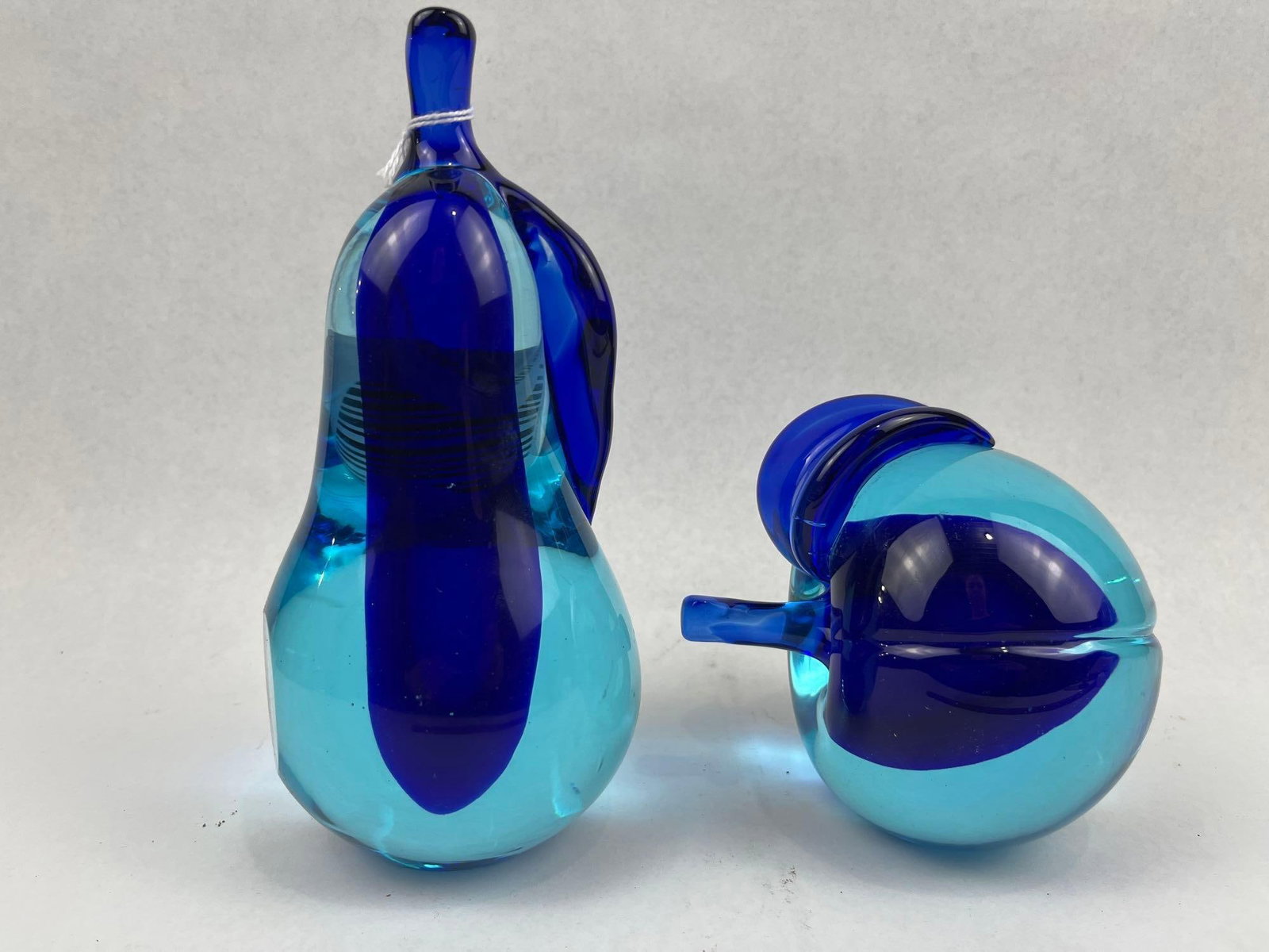 Pair Sommerso Glass Fruit Paperweights: A pair of hand-blown art glass fruit sculptures, comprising a pear and an apple. Both pieces are executed using the sommerso technique, featuring a transparent turquoise-colored casing over a solid