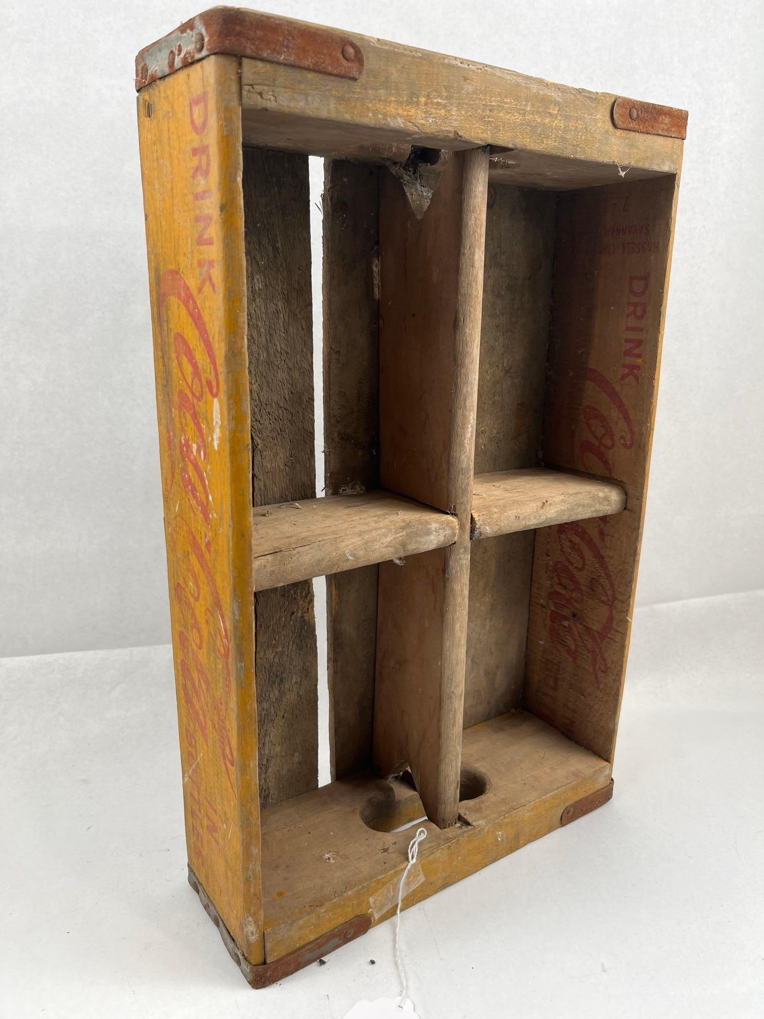 Coca-Cola 4-Compartment Bottle Crate: This wooden bottle crate features a four-compartment interior and is constructed from wood with a yellow-painted exterior and natural interior. The crate is reinforced with oxidized metal banding at