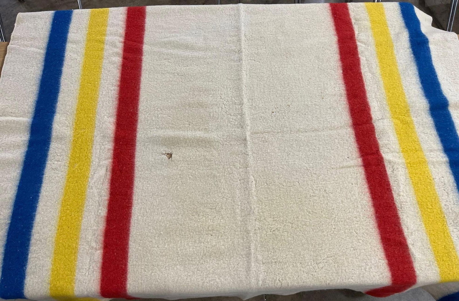 J.C. Penney Golden Dawn Striped Blanket: A vintage woven blanket composed of 100% virgin wool, featuring a cream-colored ground with a traditional multi-stripe design. The pattern consists of horizontal bands in blue, yellow, and red