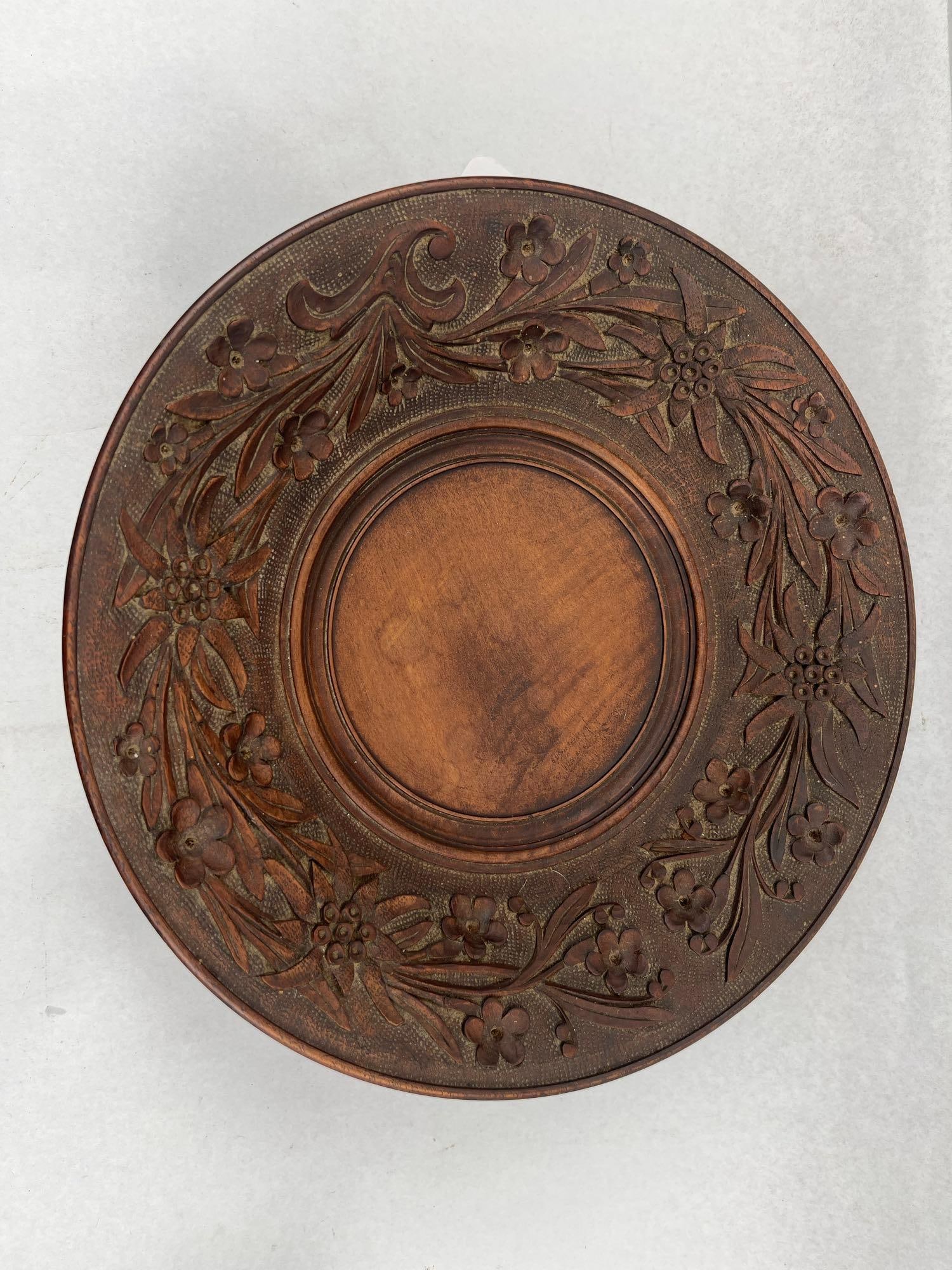 Swiss Black Forest Carved Musical Bowl: A circular carved wood musical pedestal bowl or cake stand, decorated in the Swiss Black Forest style. The wide rim is relief-carved with a continuous wreath featuring Edelweiss flowers and smaller fl