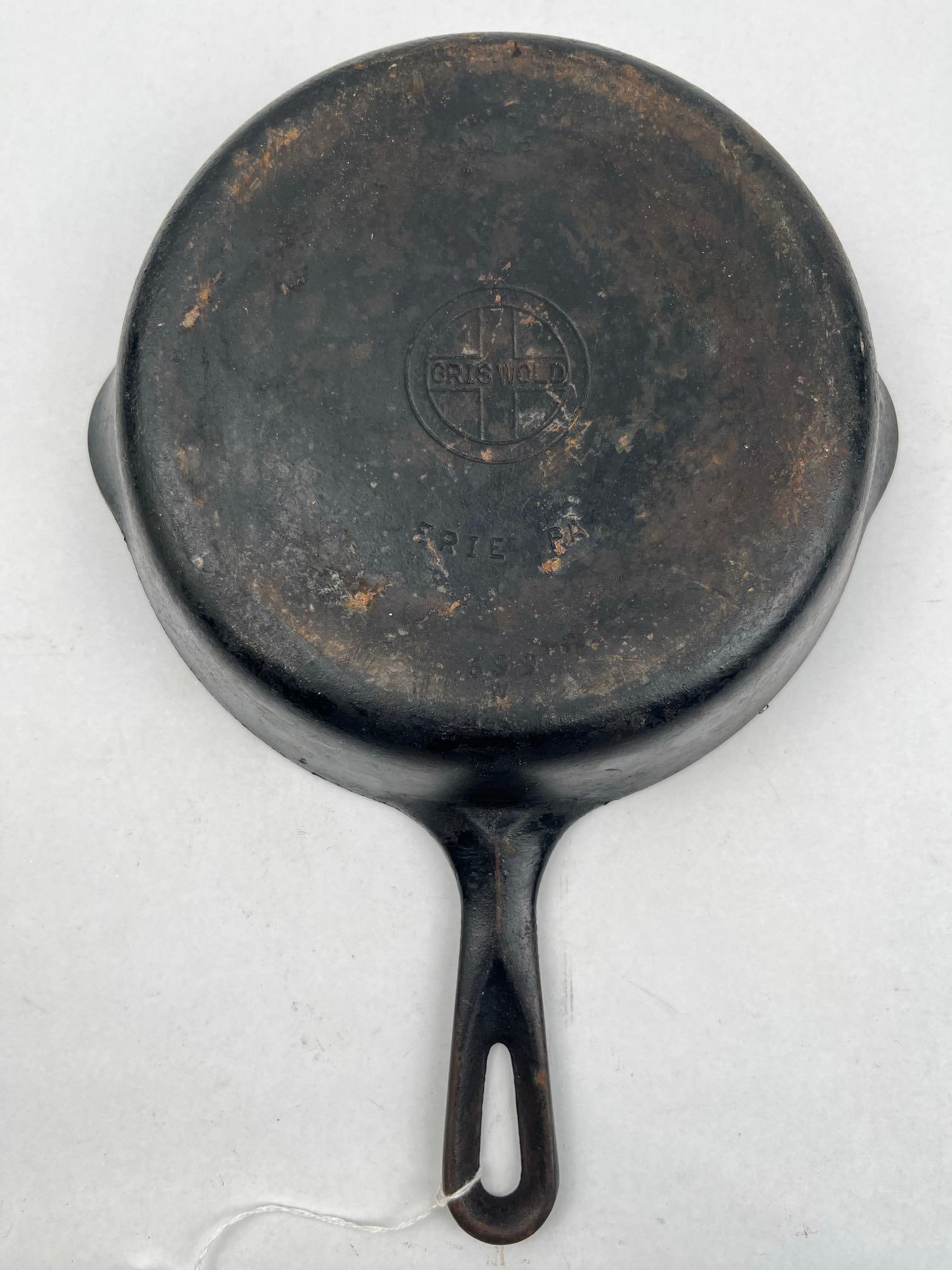 A Griswold No. 6 Cast Iron Skillet: This cast iron skillet features two integral pouring spouts and a handle with a teardrop-shaped hanging hole. The base of the skillet is marked with several impressed inscriptions. An impressed circul