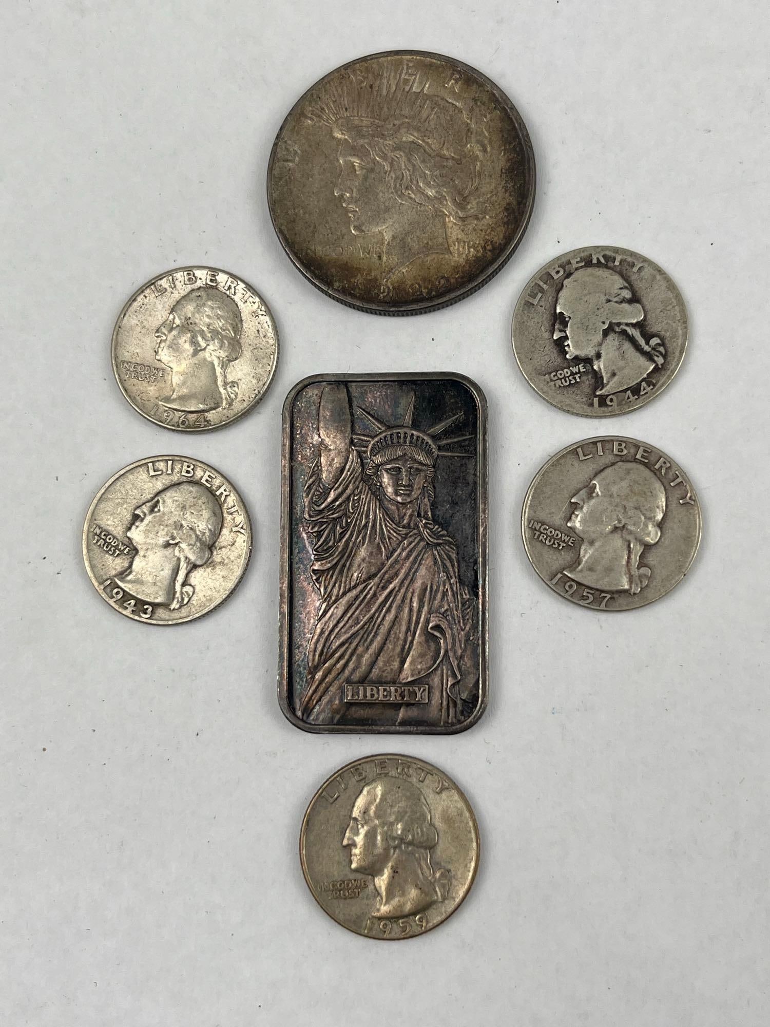 US Silver Coinage & MTB 1986 Silver Bar: A collection of United States silver items including five Washington quarters, a 1922 Peace dollar, and a rectangular silver bar. The five Washington quarters include the dates 1943, 1944, 1957, 1959,