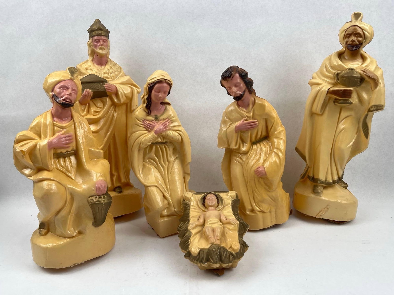 Cream Blow Mold Nativity Figurines: A group of hollow, molded plastic nativity figurines featuring an off-white or cream-colored base. The collection includes representations of the Holy Family (the Virgin Mary, Joseph, and the infant